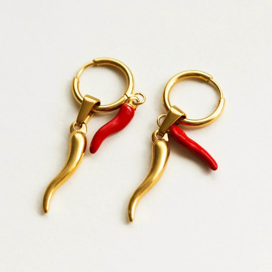 Gold earrings with red chili pepper-shaped charms on a white background