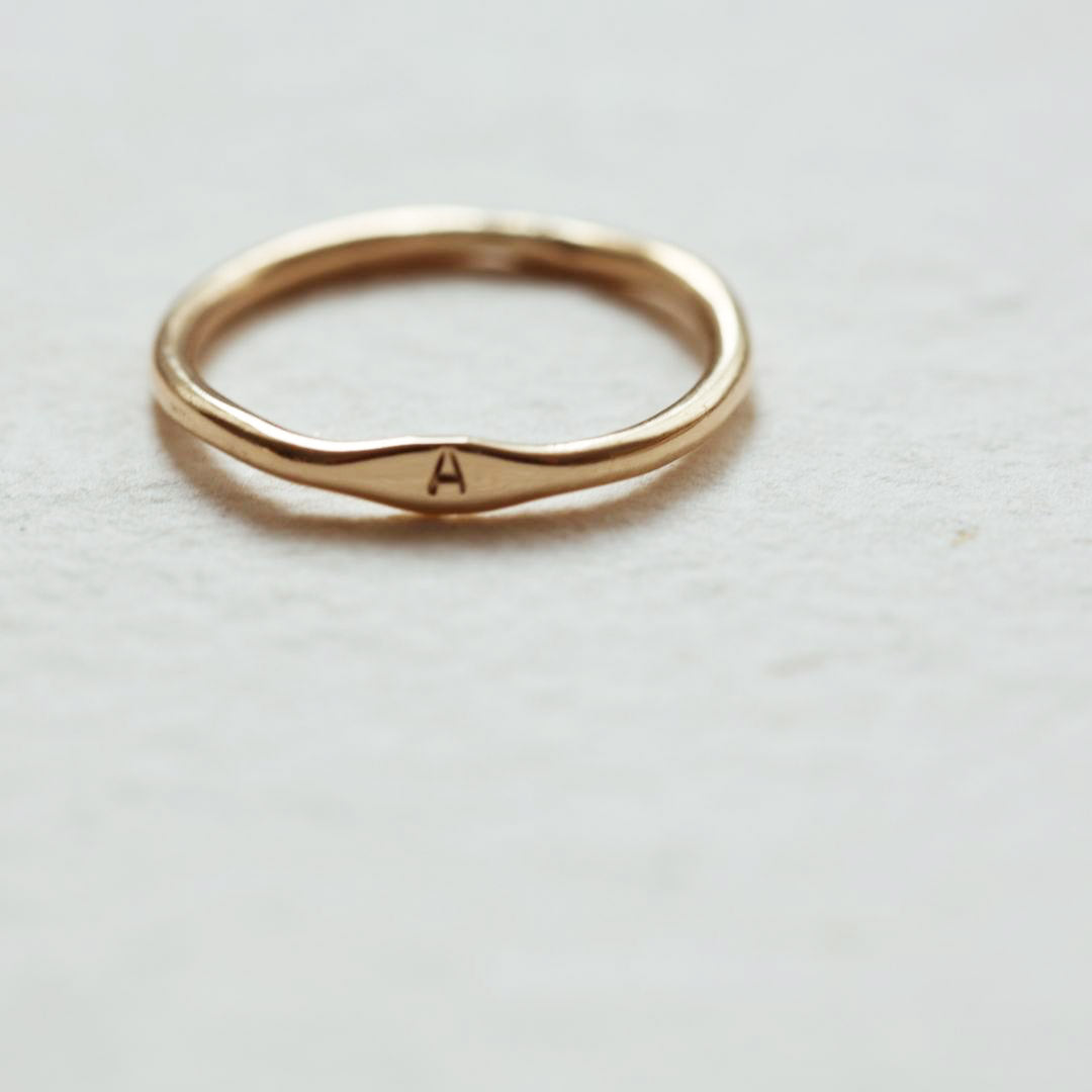 Solid Gold Dephi Ring on textured pale grey background