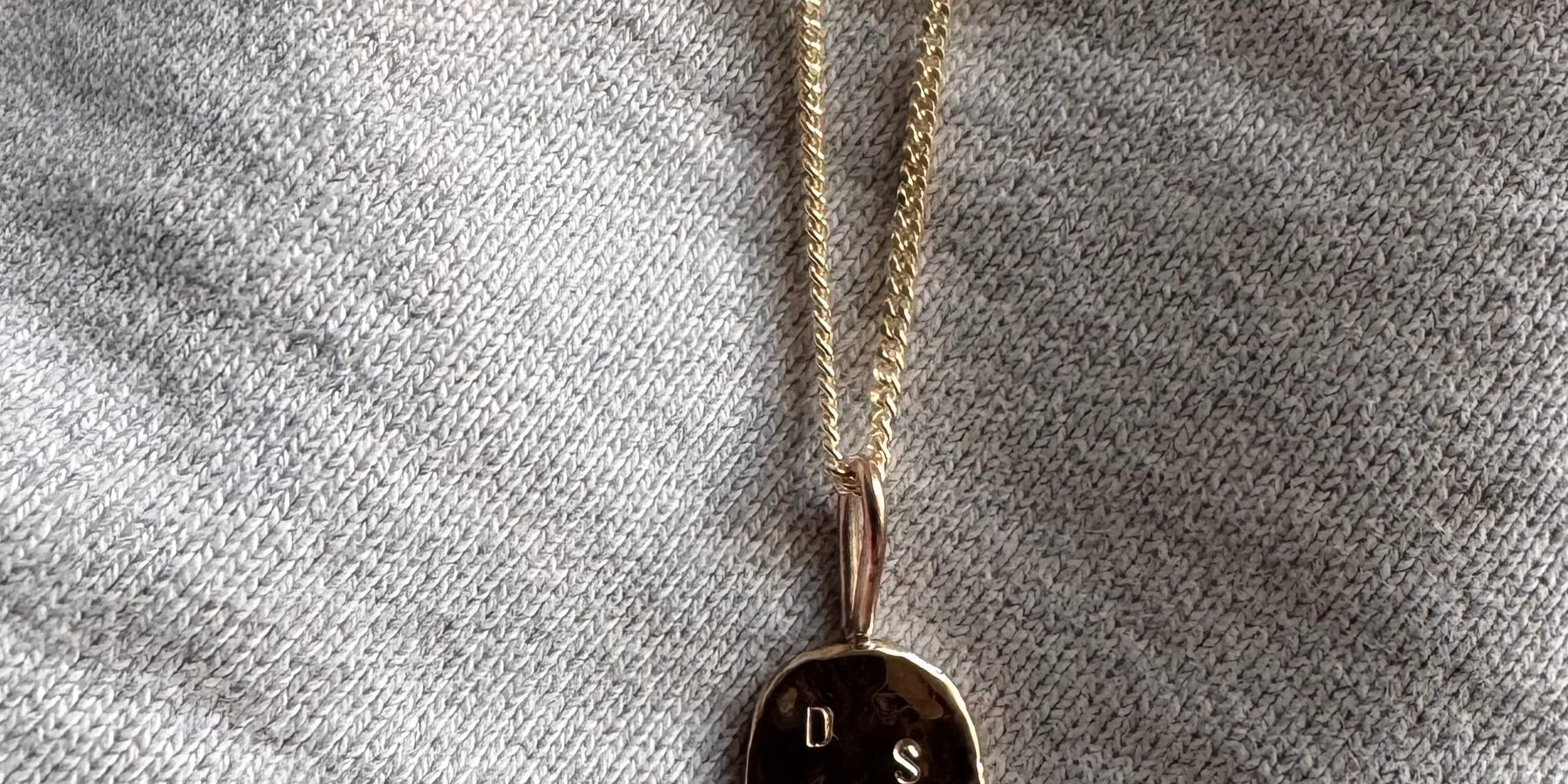 Solid gold initial pendant featuring three delicate letters on a fine chain, symbolising a personal and meaningful connection. 