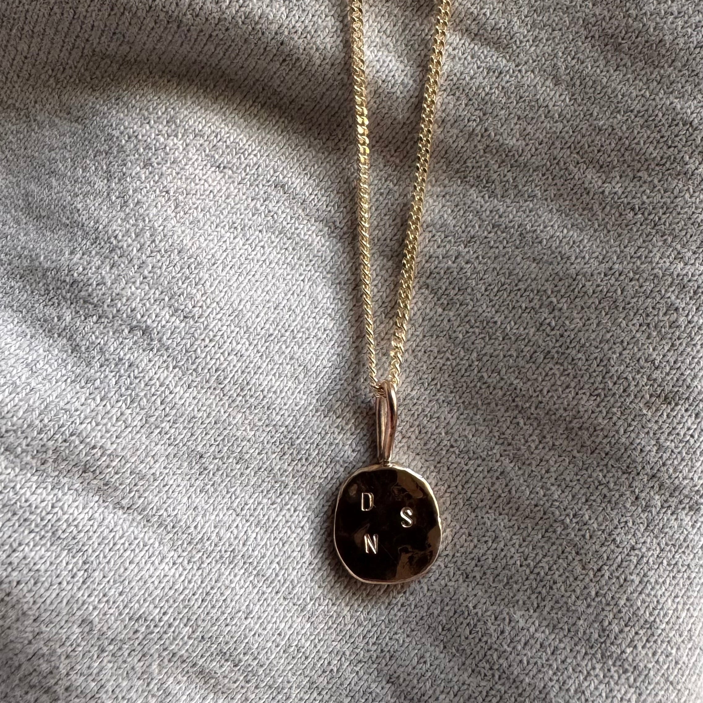 Solid gold initial pendant featuring three delicate letters on a fine chain, symbolising a personal and meaningful connection. 