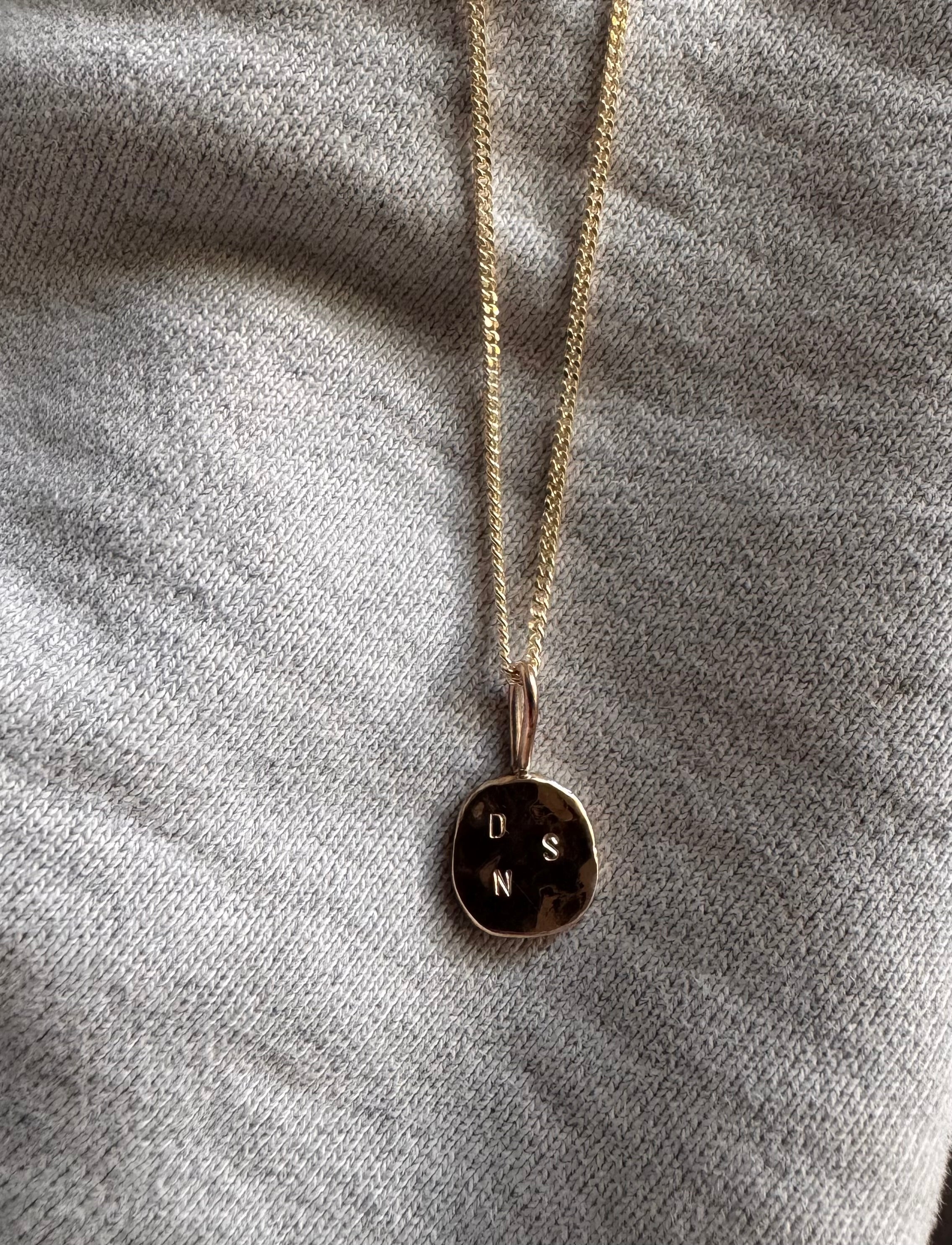 Solid gold initial pendant featuring three delicate letters on a fine chain, symbolising a personal and meaningful connection. 